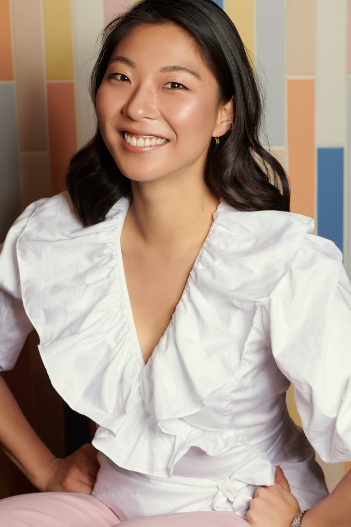 Photo of Haeni Kim in a white top, in front of a multi-coloured tiled wall